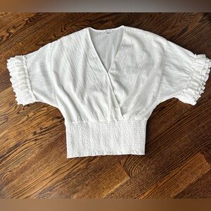 White eyelet top with gathered waist and ruffled sleeves.